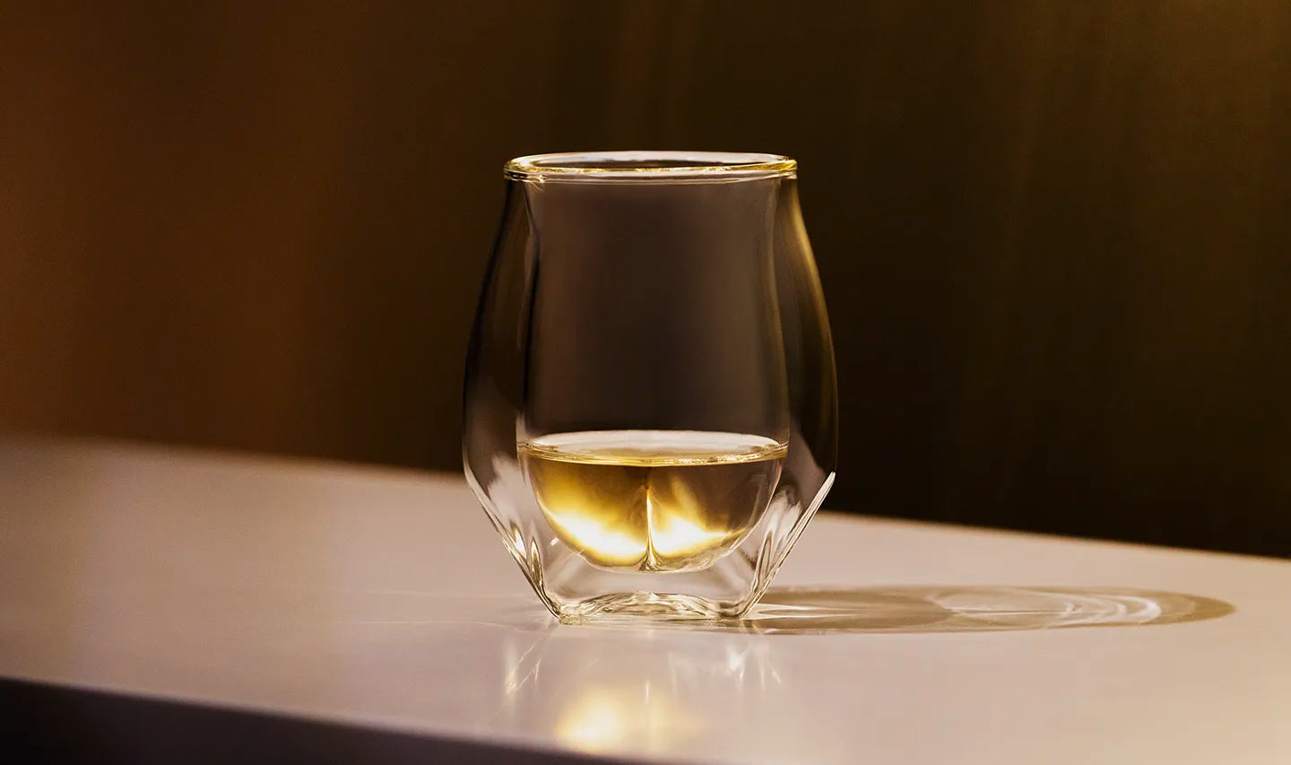 Our double-walled whisky glass filled with a golden yellow scotch enjoyed neat. 