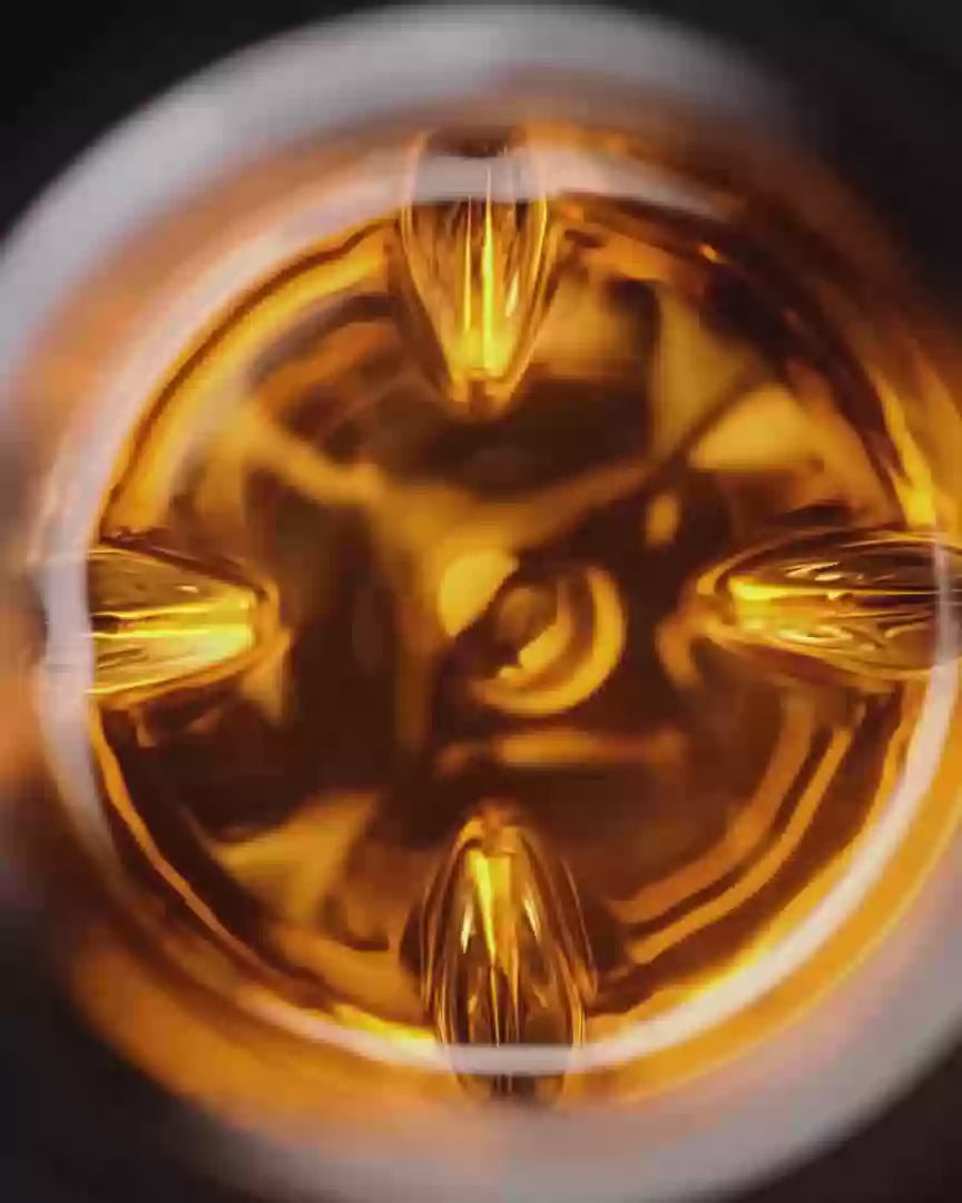  Hand slowly rotating the VAILD glass, swirling whisky inside under soft ambient light.